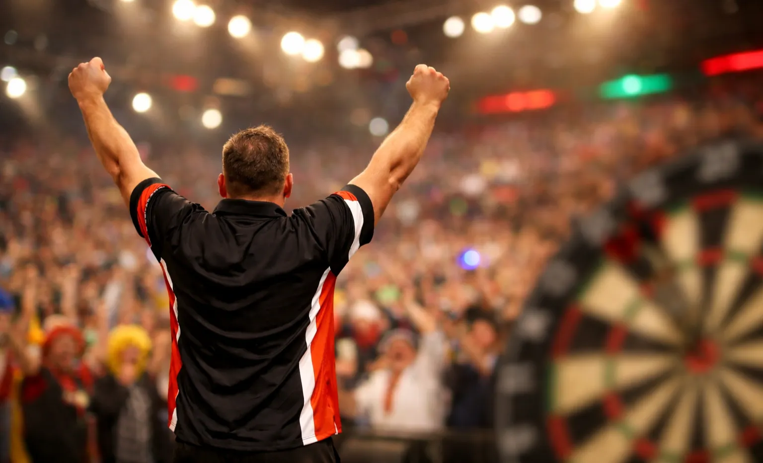 Dartsspeler viert een 180-score terwijl het publiek juicht in de arena