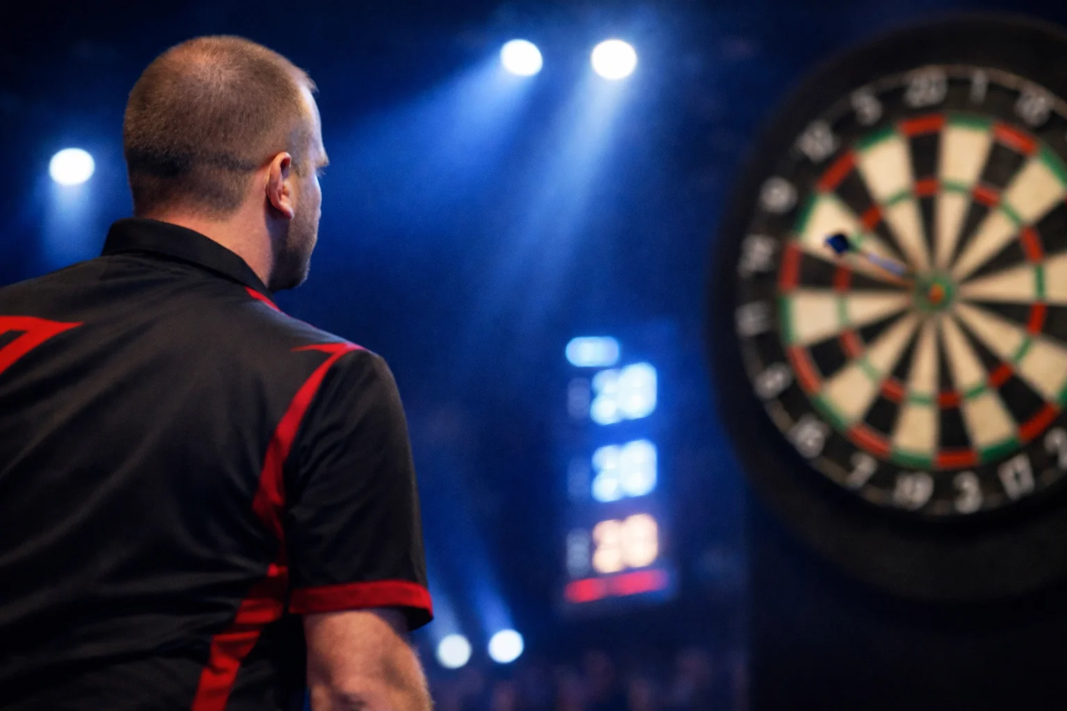 Dartspeler gooit pijl naar het bord tijdens een live wedstrijd met scorebord