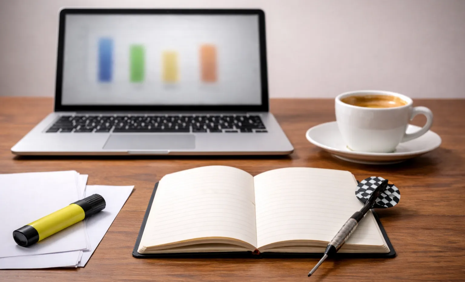 Notitieblok met dartstatistieken en een pen naast een laptop met wedstrijdgegevens